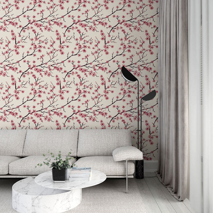 Un salon élégant avec un papier peint floral beige orné de branches noires et de fleurs roses, créant une atmosphère douce et apaisante.