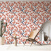 Une pièce lumineuse avec un papier peint floral aux branches noires ornées de fleurs corail, créant une ambiance douce et accueillante.