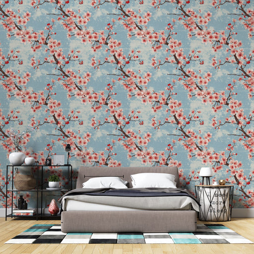 Une chambre moderne avec un papier peint floral aux motifs de branches de cerisier rose sur fond bleu, créant une atmosphère douce et apaisante.