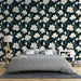 Une chambre élégante avec un papier peint floral aux grandes fleurs blanches sur fond bleu nuit, créant une atmosphère apaisante et raffinée.