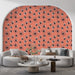 Un salon moderne avec un papier peint floral sur fond corail, présentant des fleurs noires et blanches, créant une atmosphère joyeuse et accueillante.