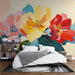 Une chambre accueillante avec un papier peint floral vibrant aux grandes fleurs jaunes, rouges et roses, créant une atmosphère joyeuse et chaleureuse.