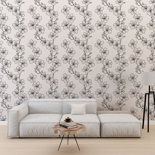 Un salon moderne avec un papier peint floral en noir et blanc représentant des branches de fleurs délicates sur un fond clair, créant une ambiance élégante et apaisante.