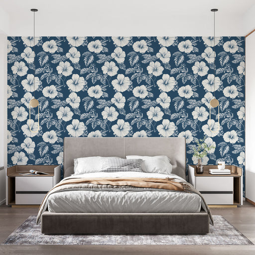 Une chambre moderne avec un papier peint floral bleu marine et blanc, illustrant de grandes fleurs exotiques qui créent une ambiance tropicale et apaisante.