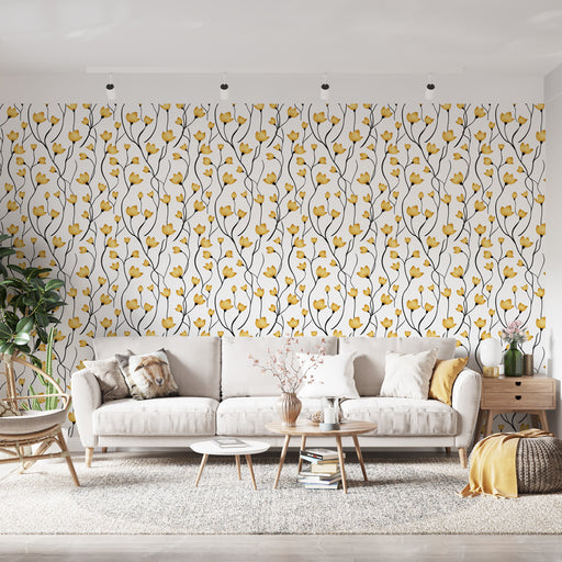 Un salon lumineux avec un papier peint floral aux motifs de fleurs jaunes sur fond blanc, créant une atmosphère joyeuse et accueillante.