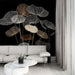 Un salon moderne avec un papier peint noir orné de délicates silhouettes de feuilles blanches et dorées, créant une ambiance élégante et artistique.