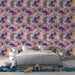 Une chambre lumineuse avec un papier peint floral aux grandes fleurs colorées dans des teintes violettes, roses et vertes, créant une ambiance joyeuse et accueillante.