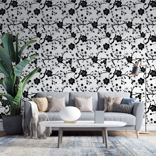 Un salon moderne avec un papier peint floral noir et blanc représentant des branches fleuries, créant une atmosphère élégante et artistique.