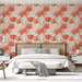 Une chambre élégante avec un papier peint floral aux grandes fleurs rouges sur fond beige, créant une atmosphère chaleureuse et accueillante.