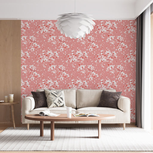 Un salon lumineux avec un papier peint floral sur fond rose, orné de délicates fleurs blanches et touches de rouge, créant une ambiance douce et accueillante.