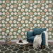 Un salon accueillant avec un papier peint floral aux roses blanches et pêche sur fond vert olive, créant une atmosphère douce et romantique.