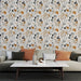 Un salon moderne avec un papier peint floral aux motifs délicats en noir, beige et terracotta, créant une ambiance chaleureuse et artistique.