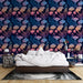 Une chambre élégante avec un papier peint floral aux teintes bleu, rose et doré sur fond marine, créant une atmosphère apaisante et artistique.