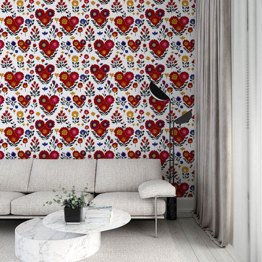Un salon moderne avec un papier peint aux motifs floraux colorés et des cœurs rouges sur fond blanc, créant une atmosphère joyeuse et chaleureuse.