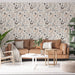Un salon lumineux avec un papier peint floral aux motifs délicats de fleurs et de papillons dans des teintes douces de beige et gris, créant une ambiance apaisante et naturelle.
