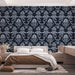 Une chambre élégante avec un papier peint floral bleu nuit et argent, aux motifs baroques raffinés, créant une atmosphère sophistiquée et chaleureuse.