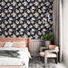 Une chambre élégante avec un papier peint floral bleu marine et crème, aux motifs de fleurs délicates créant une atmosphère apaisante et raffinée.