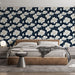 Une chambre moderne avec un papier peint floral sur fond bleu marine, présentant de grandes fleurs blanches et des feuilles délicates, créant une atmosphère élégante et apaisante.