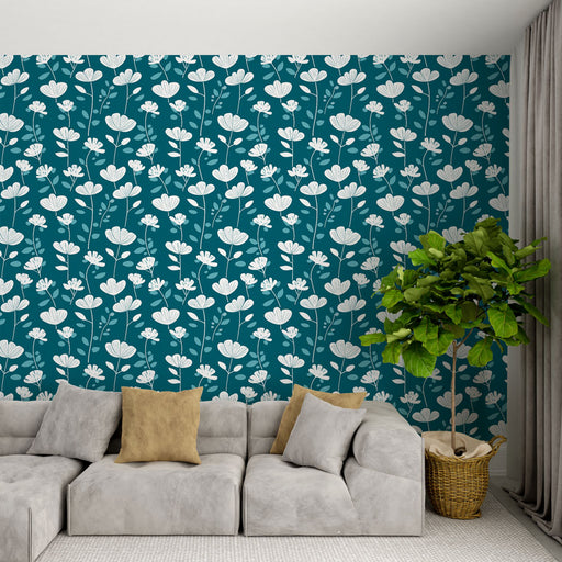 Un salon moderne avec un papier peint floral bleu canard et blanc, créant une ambiance fraîche et apaisante, agrémenté de coussins doux et d'une plante verte.