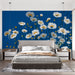 Une chambre moderne avec un papier peint floral sur fond bleu, mettant en valeur de grandes fleurs blanches et des touches dorées, créant une atmosphère fraîche et dynamique.