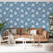 Un salon lumineux avec un papier peint floral bleu clair orné de grandes fleurs blanches, créant une ambiance douce et accueillante.