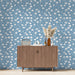 Une pièce moderne avec un papier peint floral bleu clair orné de délicates fleurs blanches, créant une ambiance douce et apaisante.