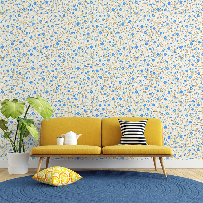 Un salon lumineux avec un papier peint floral crème orné de petites fleurs bleues et de tiges dorées, créant une ambiance fraîche et accueillante.