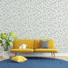 Un salon lumineux avec un papier peint floral crème orné de petites fleurs bleues et de tiges dorées, créant une ambiance fraîche et accueillante.