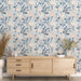 Une pièce lumineuse avec un papier peint floral aux teintes douces de bleu, rose et beige, créant une ambiance apaisante et naturelle.