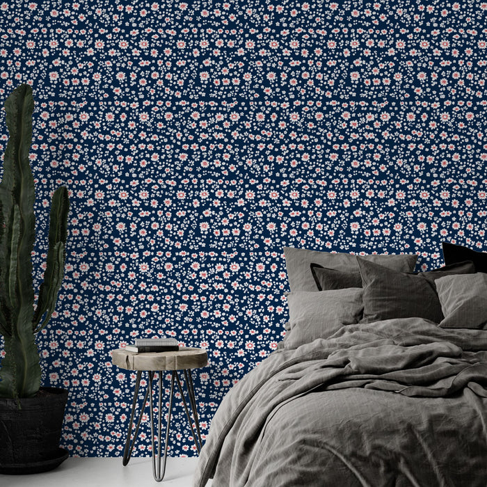 Une chambre moderne avec un papier peint floral bleu marine orné de petites fleurs roses et blanches, créant une atmosphère douce et accueillante.
