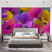 Une chambre moderne avec un papier peint floral éclatant aux grandes fleurs violettes, roses et jaunes, créant une ambiance joyeuse et vivifiante.