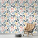 Une pièce moderne avec un papier peint floral aux motifs colorés de feuilles dans des teintes douces de rose, bleu et jaune sur fond clair.
