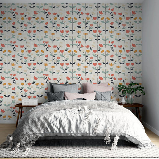 Une chambre accueillante avec un papier peint floral aux motifs colorés de fleurs roses, jaunes et vertes sur fond clair, créant une ambiance joyeuse et apaisante.