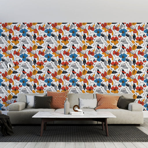 Un salon moderne avec un papier peint floral aux motifs colorés rouges, bleus et noirs sur fond blanc, créant une ambiance joyeuse et dynamique.
