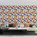 Un salon moderne avec un papier peint floral aux motifs colorés rouges, bleus et noirs sur fond blanc, créant une ambiance joyeuse et dynamique.