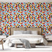 Une chambre moderne avec un papier peint floral aux motifs colorés de fleurs rouges, jaunes, noires et bleues sur fond blanc, créant une ambiance joyeuse et dynamique.