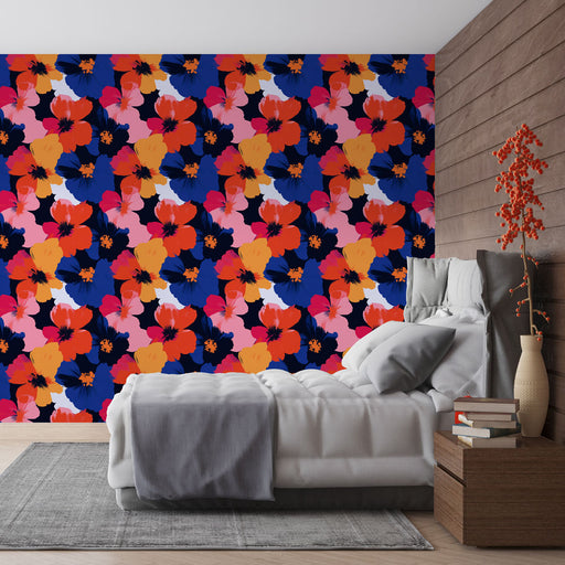 Une chambre moderne avec un papier peint floral aux couleurs vives et contrastées, mêlant des fleurs rouges, roses et bleues sur fond sombre, créant une ambiance dynamique et joyeuse.