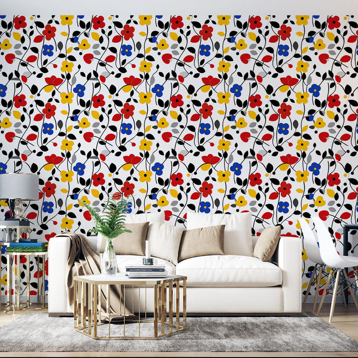 Un salon lumineux avec un papier peint floral coloré aux motifs de fleurs rouges, jaunes, bleues et noires sur fond blanc, créant une ambiance joyeuse et dynamique.
