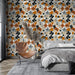 Une chambre moderne avec un papier peint floral aux motifs colorés orange, noir et gris sur fond crème, créant une ambiance chaleureuse et accueillante.