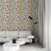Un salon moderne avec un papier peint floral aux motifs colorés de fleurs roses, jaunes et bleues sur fond clair, créant une ambiance joyeuse et accueillante.