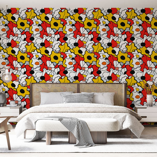 Une chambre moderne avec un papier peint coloré aux motifs floraux abstraits en rouge, jaune, noir et blanc, créant une ambiance dynamique et joyeuse.