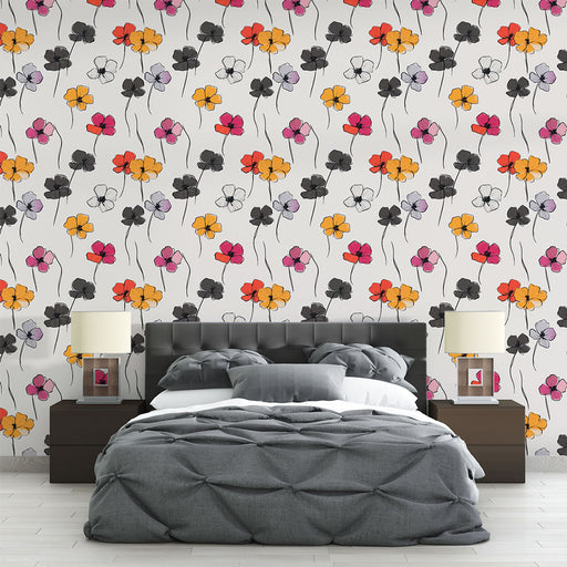Une chambre moderne avec un papier peint floral coloré aux motifs de fleurs noires, jaunes, rouges et violettes sur fond blanc, créant une ambiance joyeuse et dynamique.