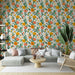 Une pièce de vie lumineuse avec un papier peint floral aux motifs colorés de fleurs orange, roses et vertes sur fond clair, créant une ambiance joyeuse et accueillante.