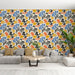 Un salon moderne avec un papier peint floral aux motifs colorés de bleu, orange, jaune et noir sur fond clair, créant une ambiance joyeuse et dynamique.