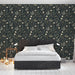 Une chambre moderne avec un papier peint floral sur fond noir, aux motifs délicats de fleurs et de feuillages dans des teintes crème et vert, créant une atmosphère chaleureuse et accueillante.