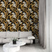 Un salon élégant avec un papier peint floral noir, or et blanc, présentant des motifs de fleurs et de feuilles qui créent une atmosphère luxueuse et chaleureuse.