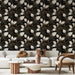 Un salon moderne avec un papier peint floral noir, orné de motifs de feuilles blanches et dorées, créant une ambiance élégante et sophistiquée.