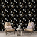 Un salon élégant avec un papier peint floral noir orné de fleurs blanches et de feuillages dorés, créant une atmosphère chic et apaisante.