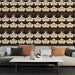 Un salon élégant avec un papier peint art déco noir et doré, présentant des motifs floraux stylisés qui créent une ambiance sophistiquée et chaleureuse.