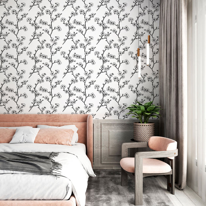Une chambre élégante avec un papier peint floral noir et blanc représentant des branches délicates, créant une atmosphère douce et apaisante.